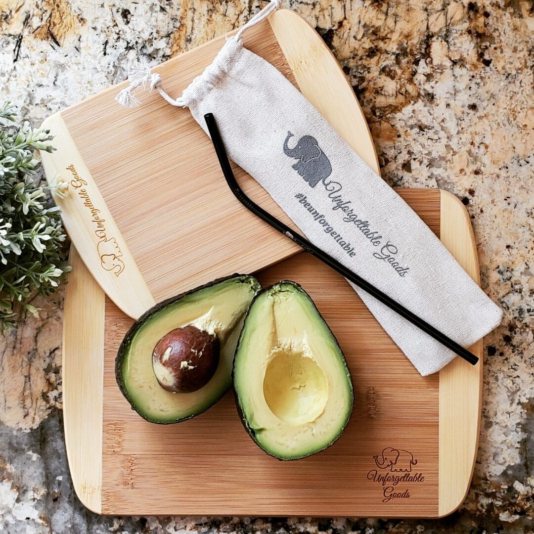 A cutting board with an avocado cut in half.