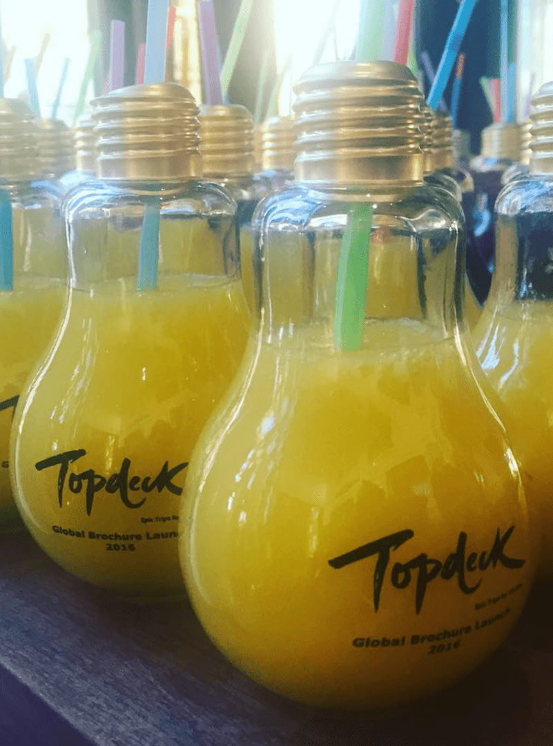 A row of yellow drinks in glass bottles.